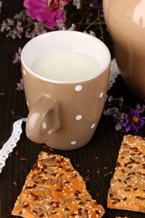 Pitcher and cup of milk with cookies on wooden table close-up