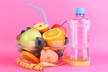 Glass bowl with fruit for diet, measuring tape and water bottle