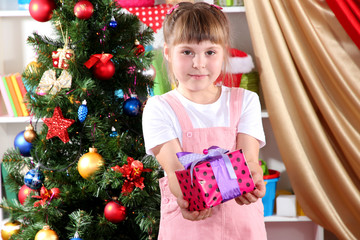 Little girl with Christmas toys in festively decorated room
