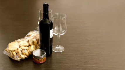 a bottle of wine with a couple of glasses, pate and croutons