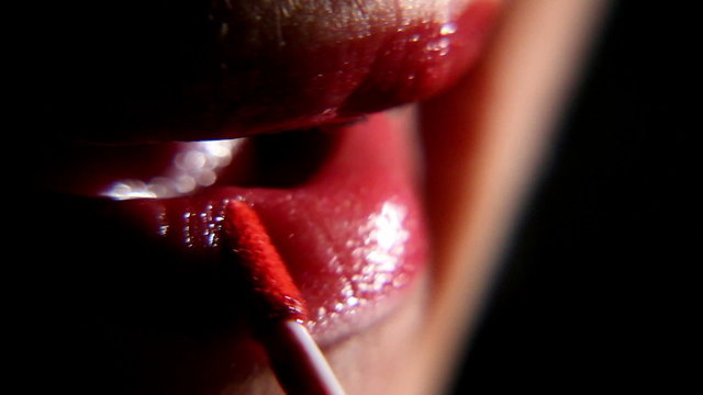 woman paints her lips with lipstick on a black background 3