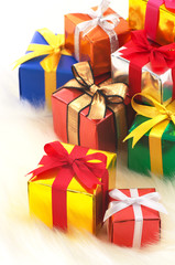 Many gifts on white fake fur background.