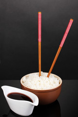 Bowl of rice and chopsticks on grey background