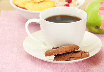 cup of coffee with cookies and fruits on table