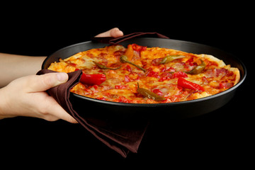 hands holding pepperoni pizza in pan isolated on black