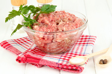 Bowl of raw ground meat with spices on wooden table