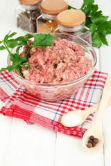 Bowl of raw ground meat with spices on wooden table