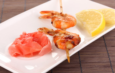 Shrimp skewers on plate with ginger and lemon