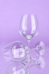 Two empty wine glasses on color background