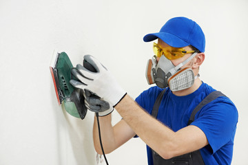 worker with orbital sander at wall filling - obrazy, fototapety, plakaty
