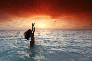 Woman splashing in sea on sunset