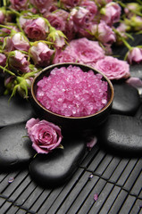 Obraz na płótnie Canvas Pink herbal salt in bowl and bouquet rose and stones on mat