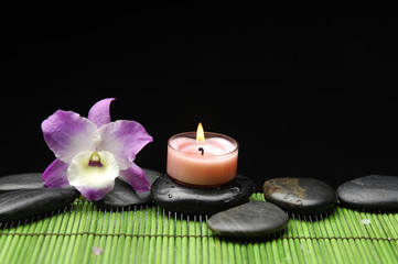 Fototapeta na wymiar Candle and pink orchid with black stone on green mat