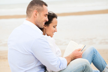 Couple reading book on the beach