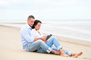 Couple reading book on the beach