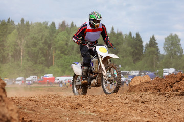 Young man wearing in helmet on dirt motorcycle jumps