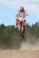 Cyclist wearing in helmet on dirt motorcycle jumps