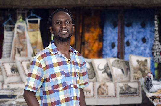 african curio salesman vendor  in front of ethnic wildlife items