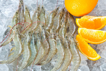Fresh white shrimps and orange chilled on ice