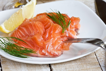 Salmon on white plate with lemon on wooden  background