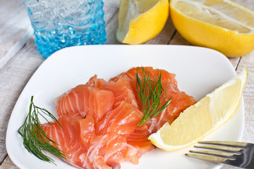 Salmon on white plate with lemon on white background