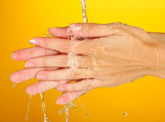 Fototapeta premium Washing hands on orange background close-up