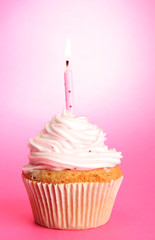 tasty birthday cupcake with candle, on pink background