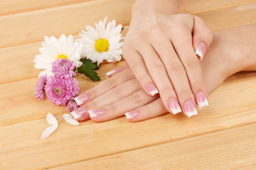 Obraz na płótnie Canvas Ręce kobiety z french manicure i kwiaty