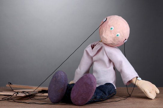 Wooden puppet sitting on grey background