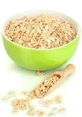 Green bowl full of oat flakes with wooden scoop isolated