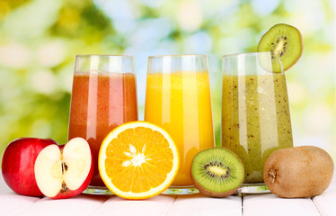 fresh fruit juices on wooden table, on green background