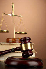 Golden scales of justice, gavel and books on brown background