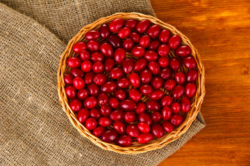 fresh cornel berries on wicker mat on wooden background