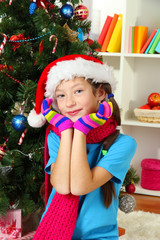 Little girl with pink scarf and multicolor gloves sitting near