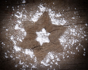 Christmas star made of sugar dust over wooden background