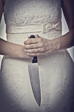  detail of a bride holding a kitchen knife in her hands. concept of hostility, aggression domestic danger.