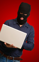 young male thief holding laptop
