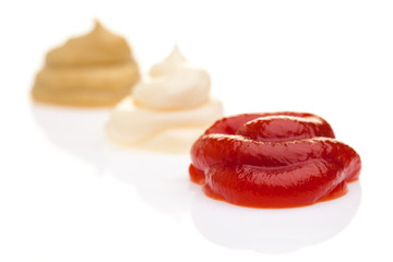 Ketchup, Mayonnaise und Senf diagonal auf weißem Hintergrund