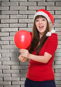 Surprised woman wearing a christmas hat and holding a balloon
