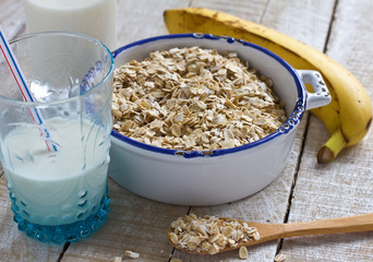 Oat flakes in bowl with banana and milk