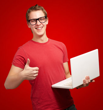 Man holding laptop with thumbs up