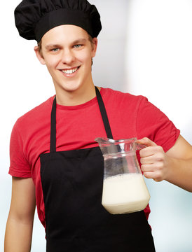 portrait of young cook man holding milk jar indoor