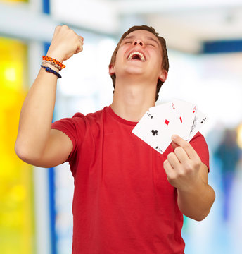 portrait of young man doing a winner gesture playing poker indoo