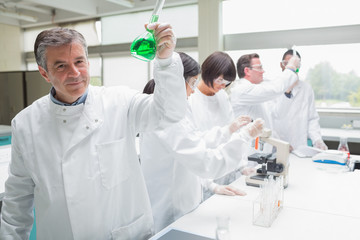 Chemist raising beaker of green liquid