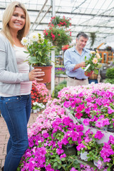 Couple holding plants while smiling