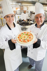 Chef's presenting a pizza