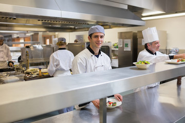 Smiling chef garnishing a salad