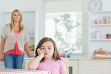 Child at kitchen table looking angry