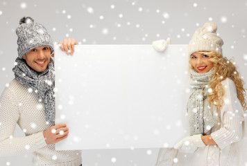 couple in a winter clothes holding blank board