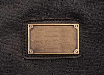 metal label on old black leather background